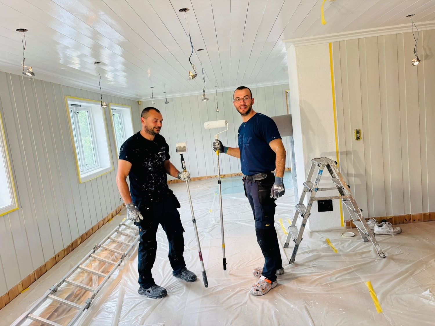 To håndverkere fra Oslo Håndverksmester AS i arbeid med å male tak og vegger